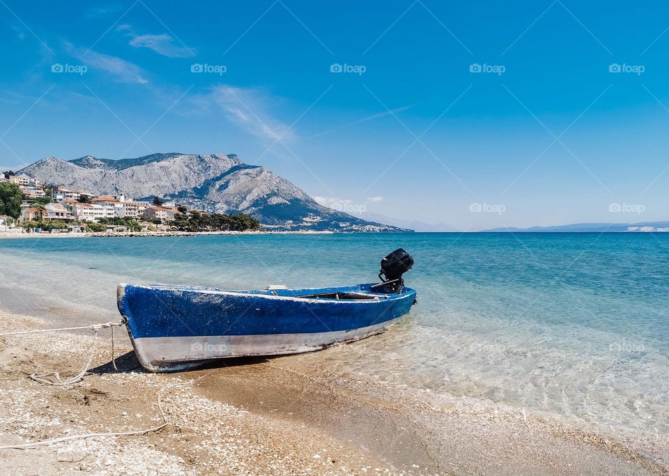 Old boat on empty beach with beautiful turquoise sea on Adriatic coast near Omiš in Croatia