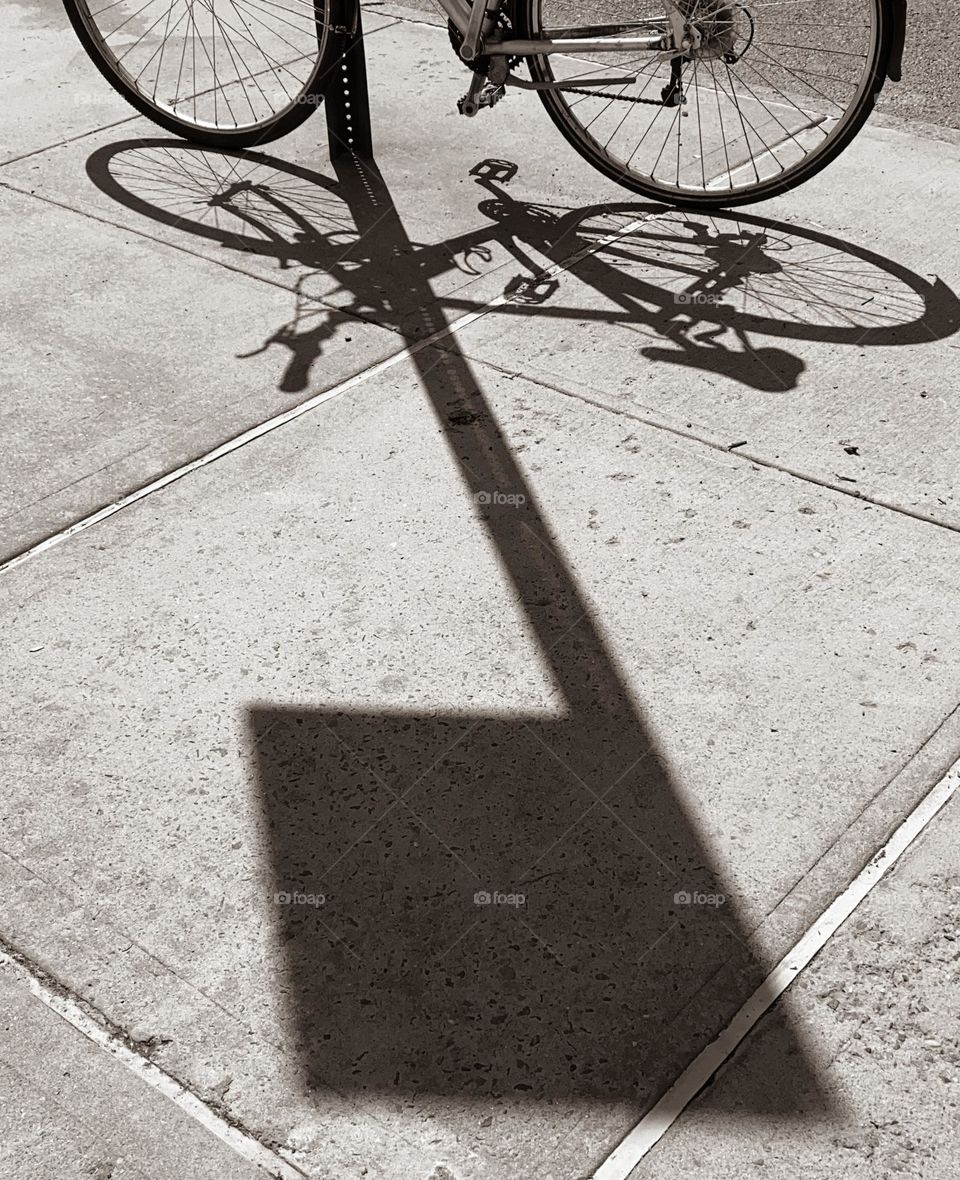 Bicycle Parking and its shadow leaning on a post, Manhattan New York.