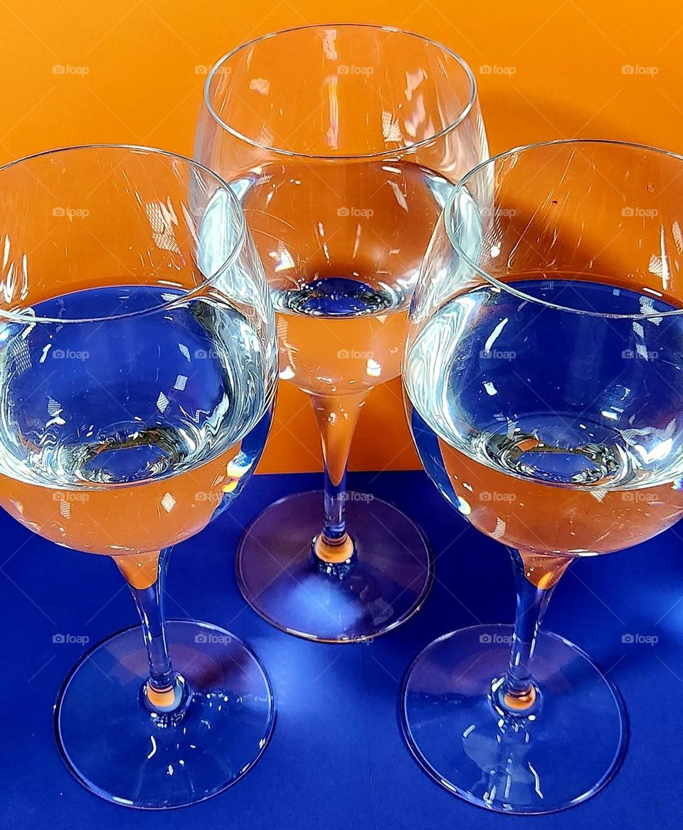 Orange and blue complementary colours composition made with orange and blue papers reflecting in half filled water glasses
