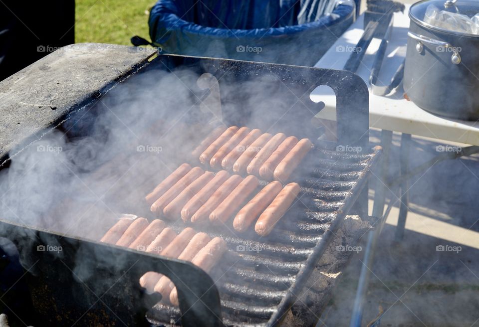 Hot dogs on a smoky barbecue grill outdoors 