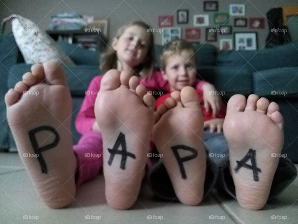 Brother and sister sitting with text papa on there feet