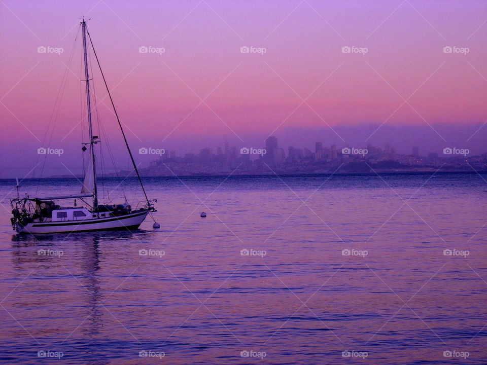 Sail boat sailing on sea at sunset