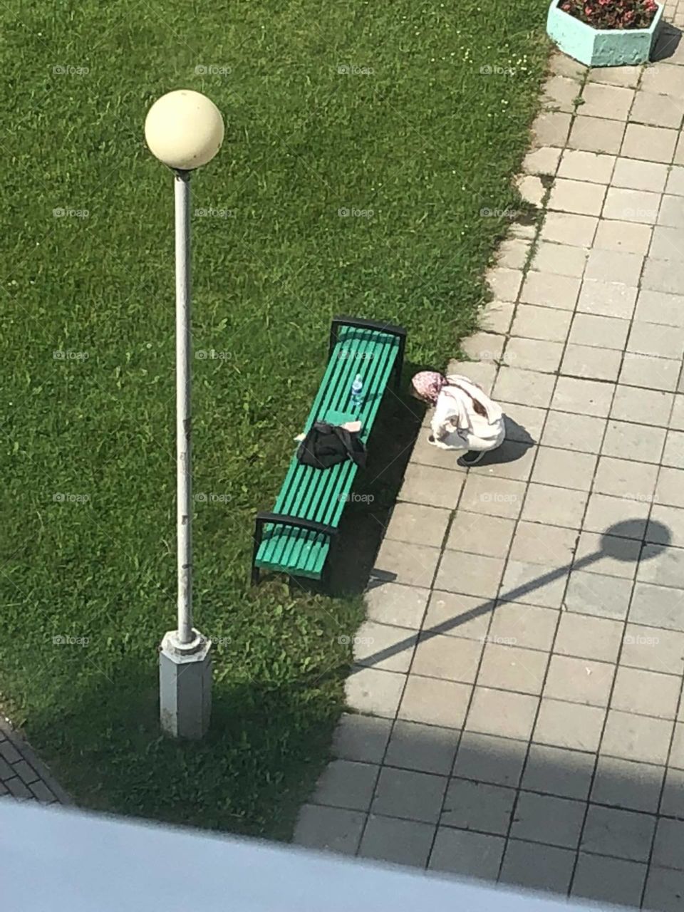 top view-a girl draws near a bench and a shadow from a lantern