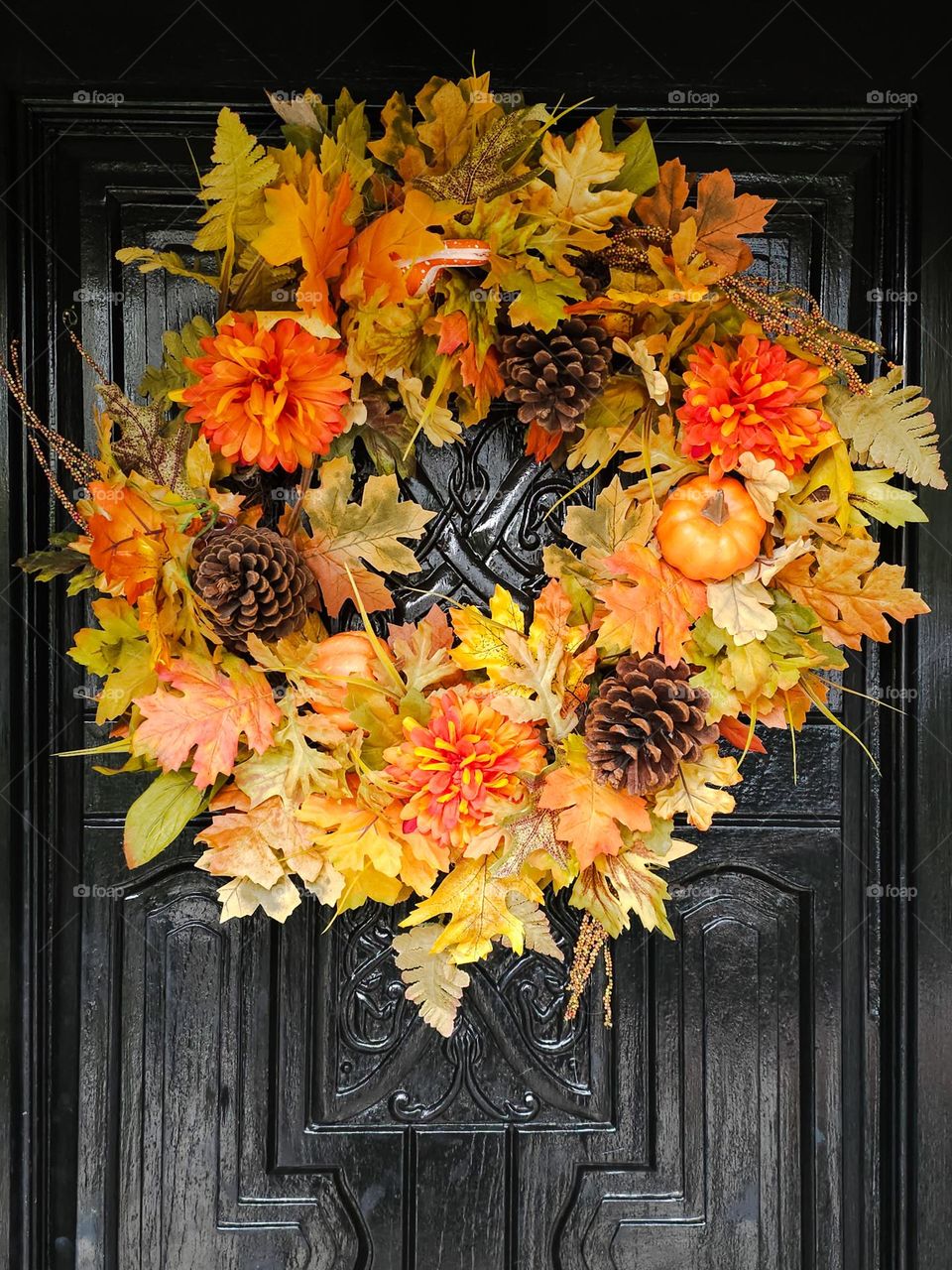 beautiful and festive fall wreath adorning a black door with the colors of autumn on full display