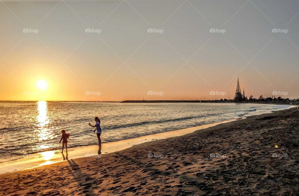 Silhouettes and shadows: girl and mother  
had a happy time at the seashore sunset.