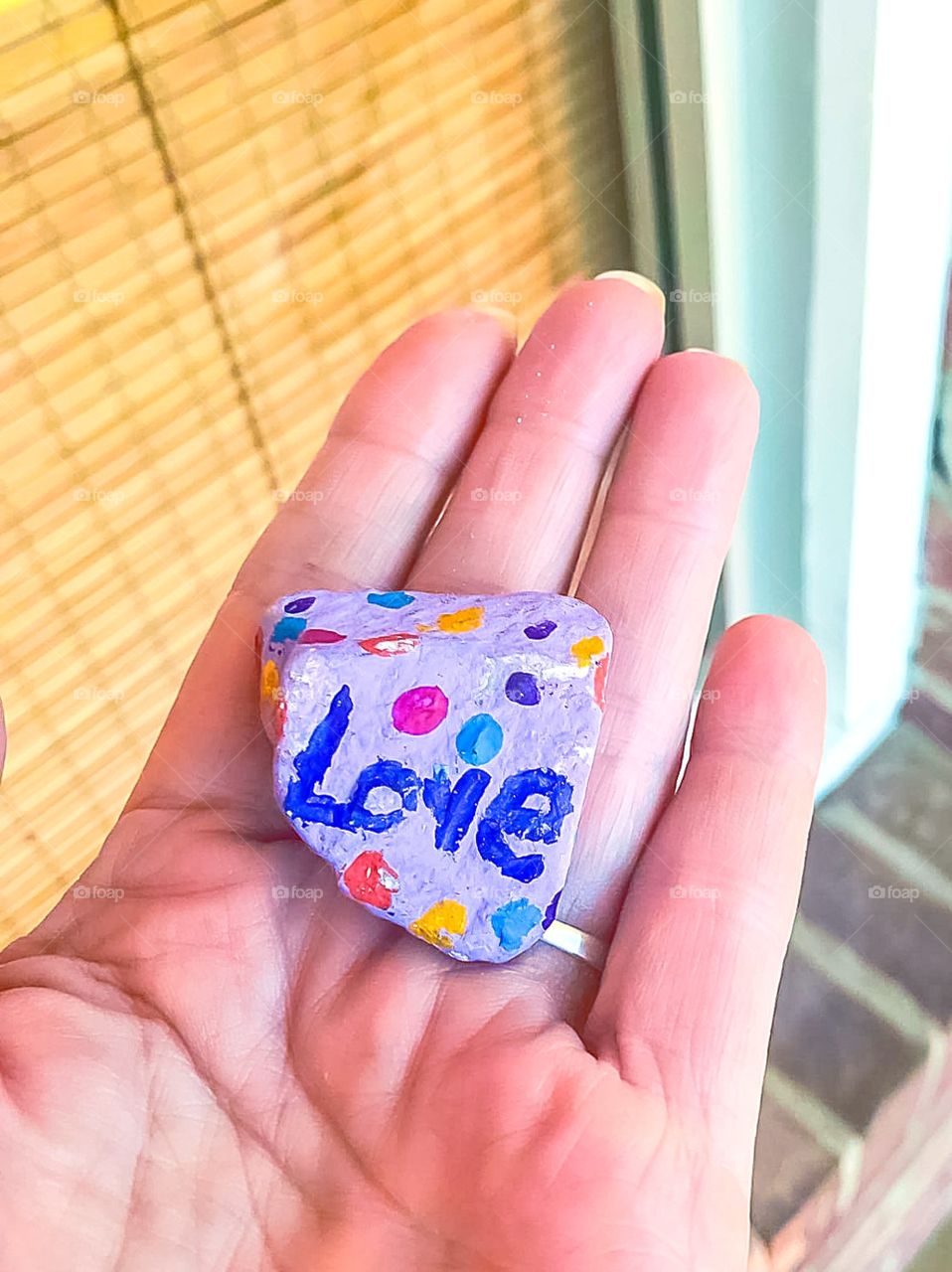 holding rock in hand with the word love painted on it