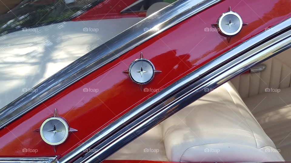 The detail of a rear window panel of a classic red Ford Galaxie Starliner