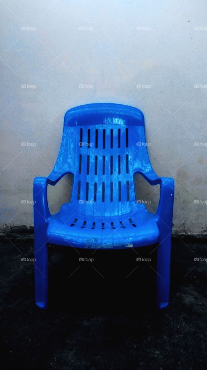 Blue plastic chair with concrete wall