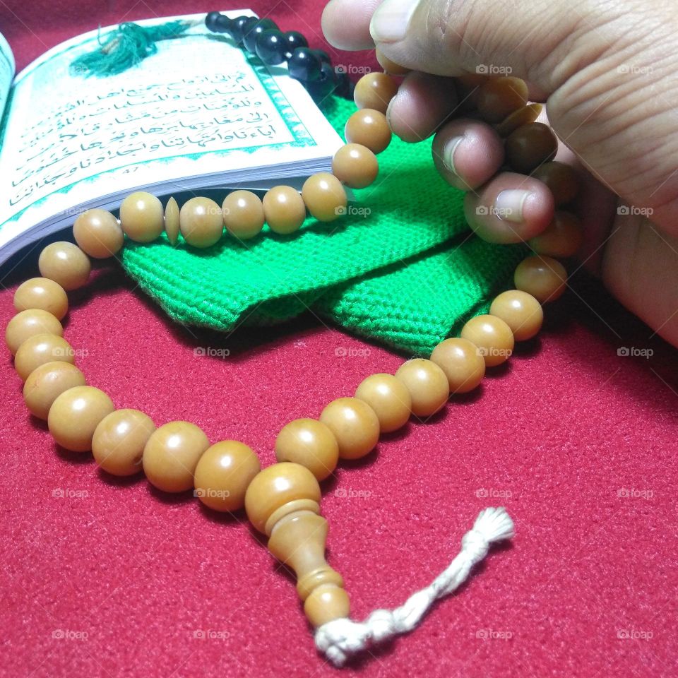 Hand with prayer bead and green cap