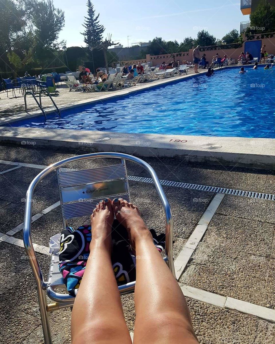 Relaxing by the swimming pool on a hot, sunny day in Salou, Spain. Legs and feet shot.
