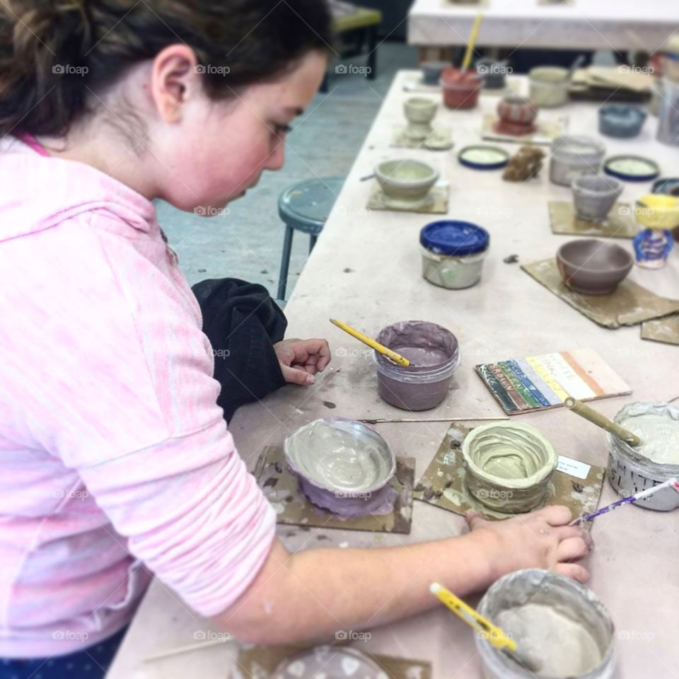 Girl creating clay bowls and painting in class