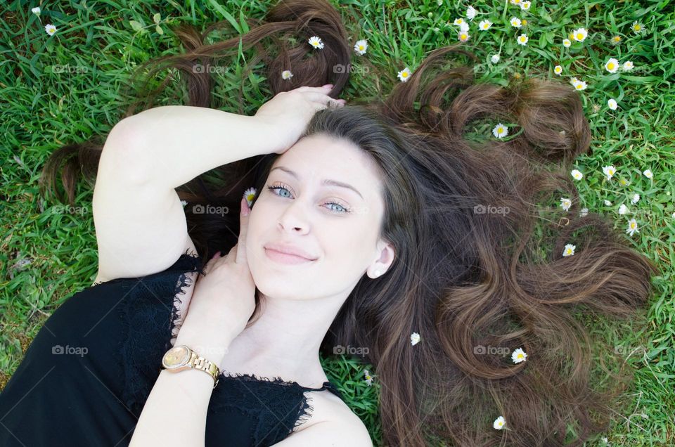 Woman with beautiful natural long hair on a background of daisies