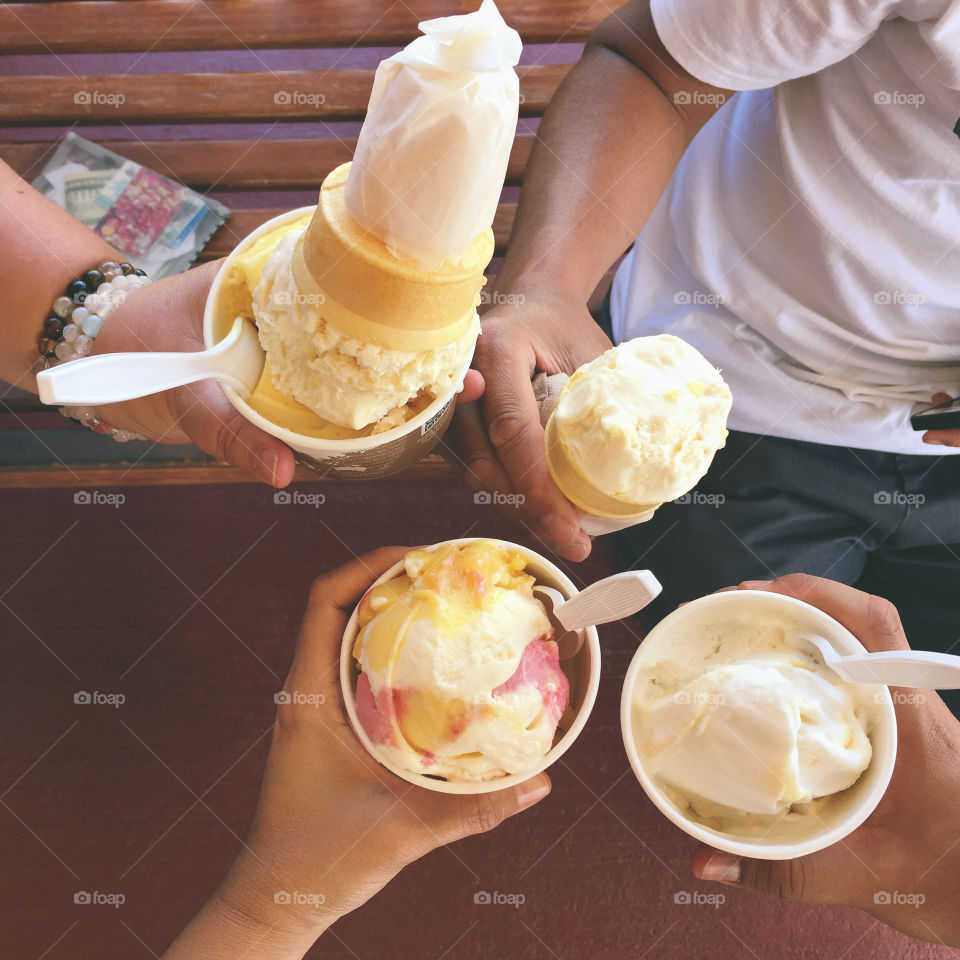 Ice cream with friends. Group of people holding ice cream in hands. Summer outing. Ice cream cones and ice cream cups. 