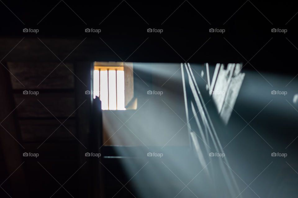 Sunrays emerging through wooden window.