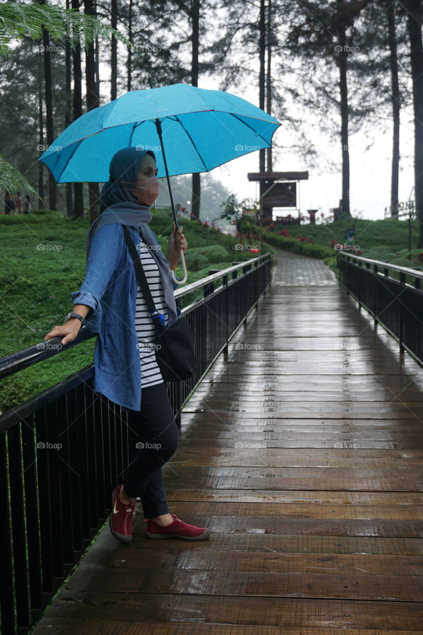 woman with umbrella walk in forest after rain