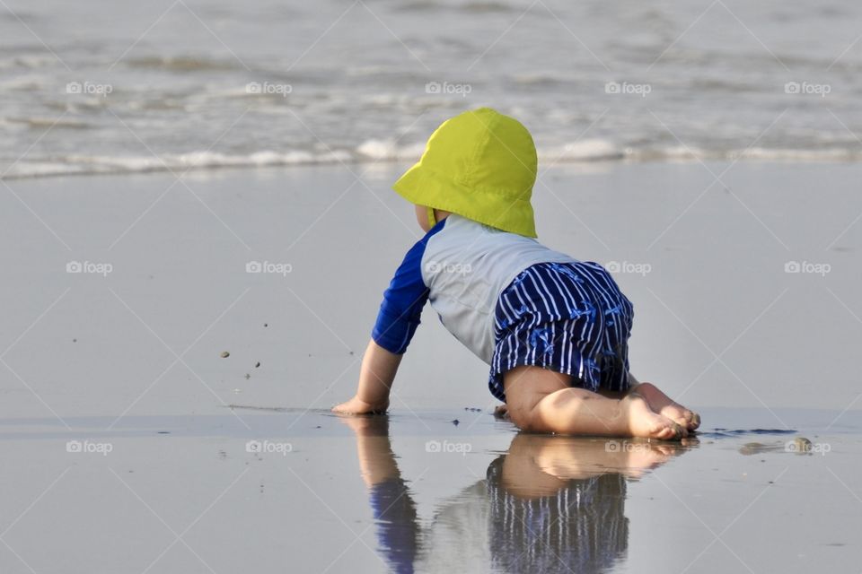  A baby crawling on the beach going toward the ocean