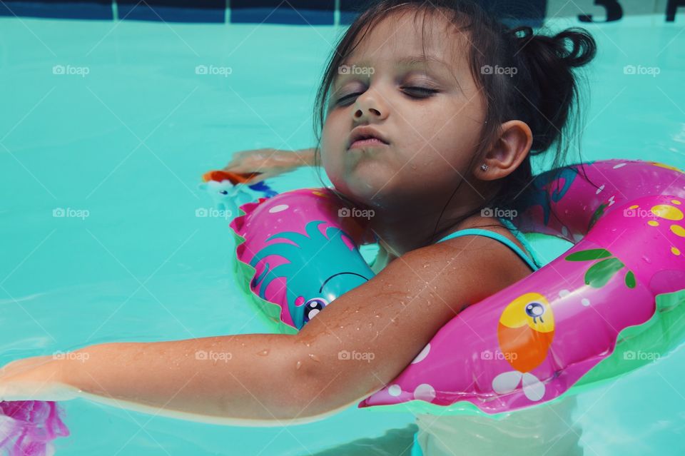 Girl swimming in pool with inflatable tube