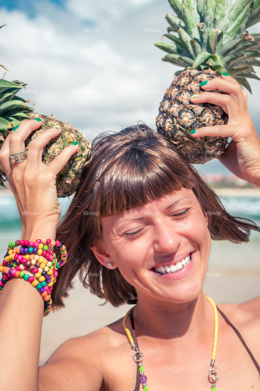 Funny girl having fun on the beach with pineapples.
