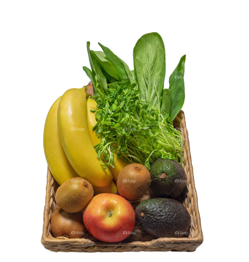 Fresh vegetables and fruits in a basket such as: bananas and kiwis, wheat germ, avocado, spinach and apple