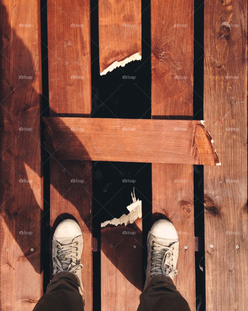 Low section view of human leg standing on boardwalk