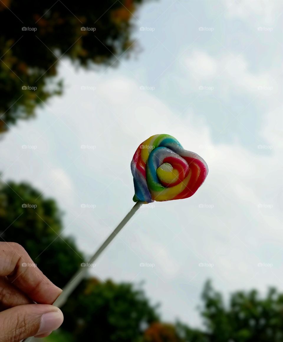 Rainbow candy against sky background