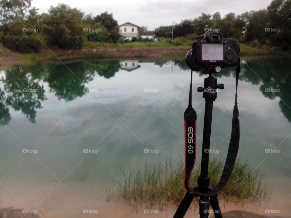 professional photographet set up camera canon 6d and tripod for long exposure shoot of a water pond reflection