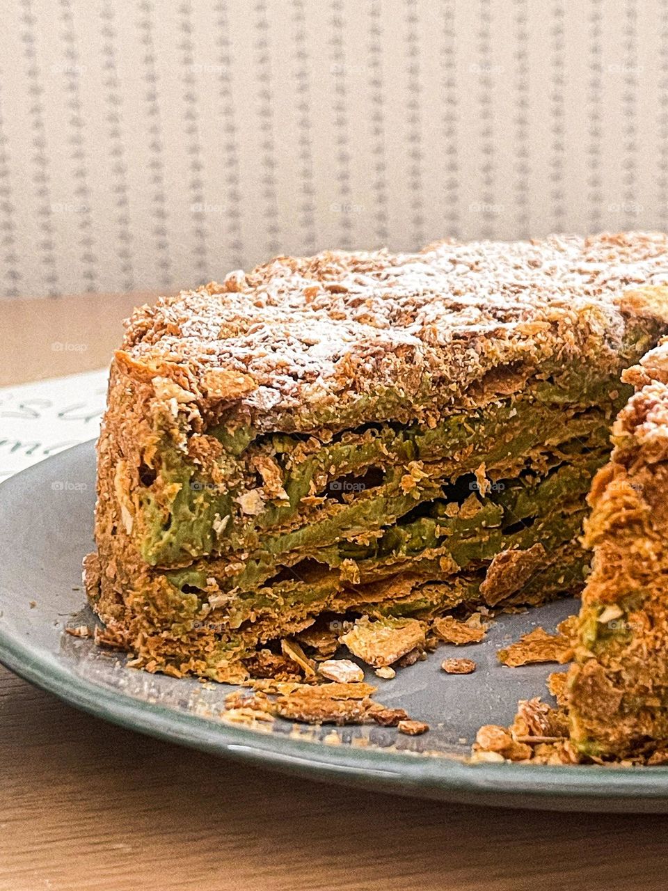 Napoleon cake with pistachio creme on the plate cut