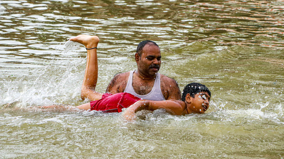 A lovable father doing his duty correctly with love and care.. Teaching to swim