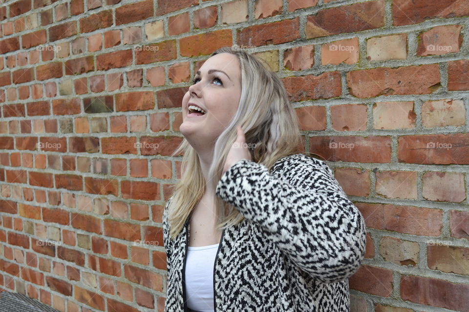 Woman standing against brick wall and looking up