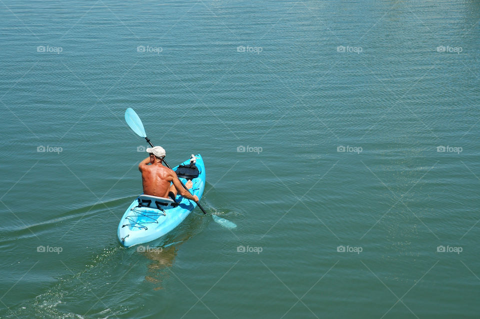 A man kayaking in smooth waters. 