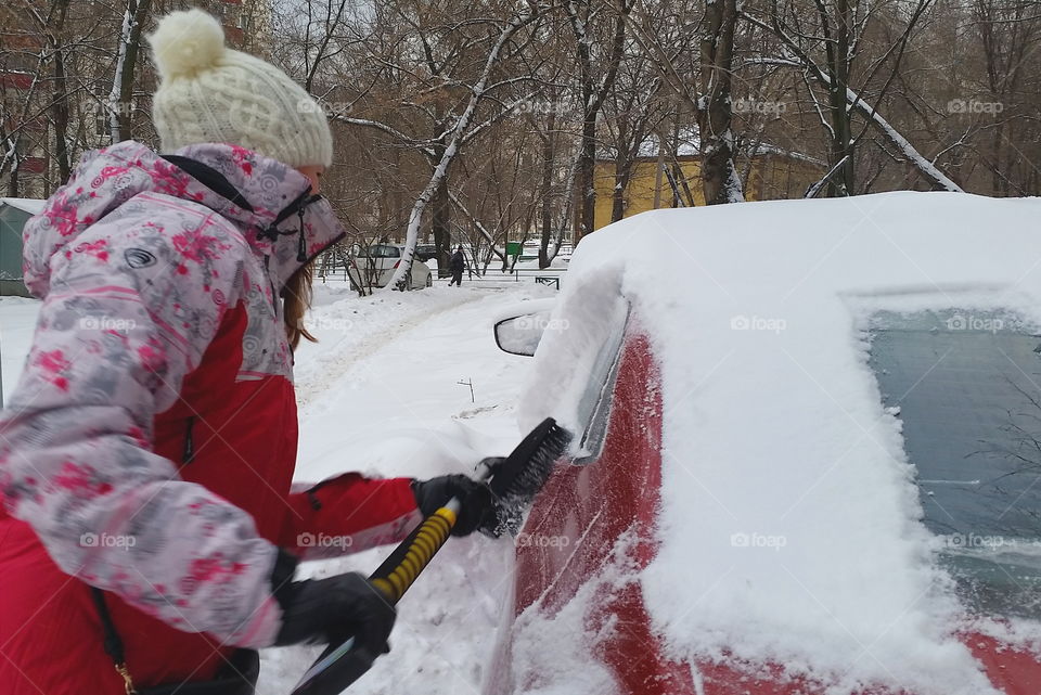 Girl cleaning car from the snow