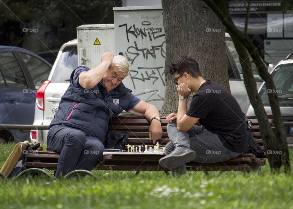 Two generations playing chess outdoor