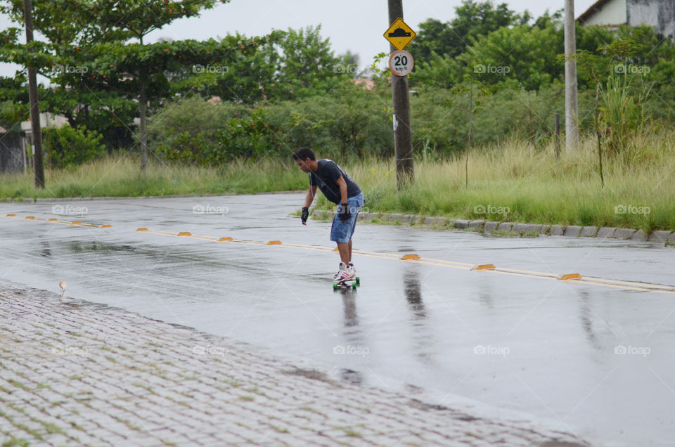 Male skateboarding on wet road