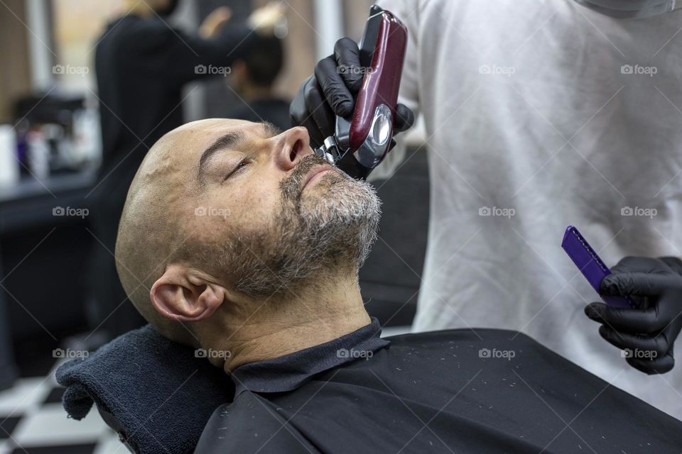 Man having a beard trim in the barbershop 