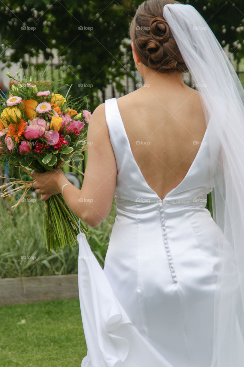 The back of a bride holding a wildflower bouquet