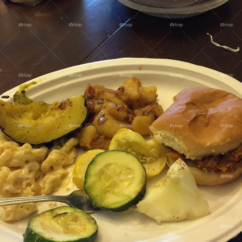 Summer foods for a picnic, including zuchinni, hamburg and bun.