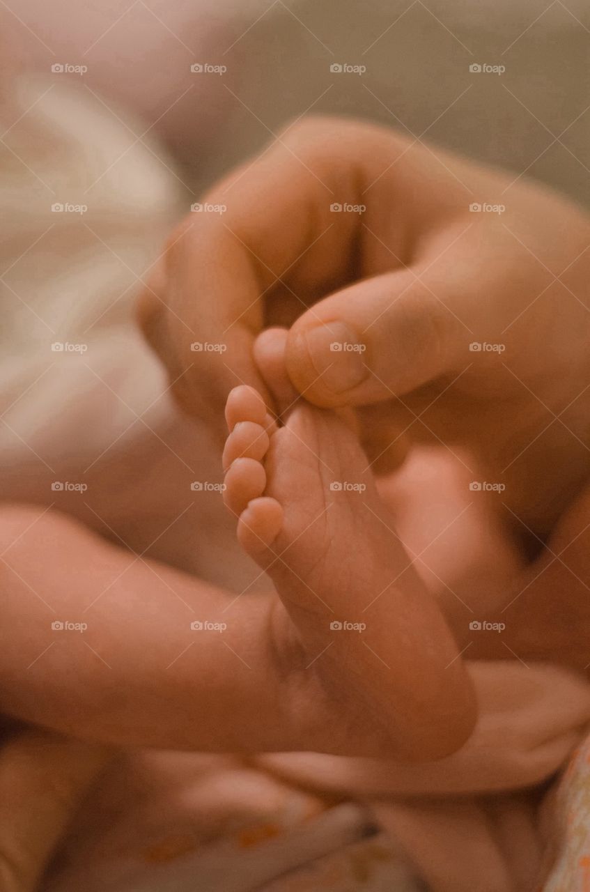 Woman's hand holding baby's feet