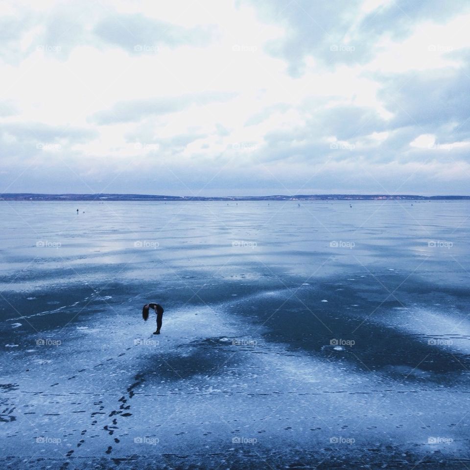 Frozen sea against cloudy sky