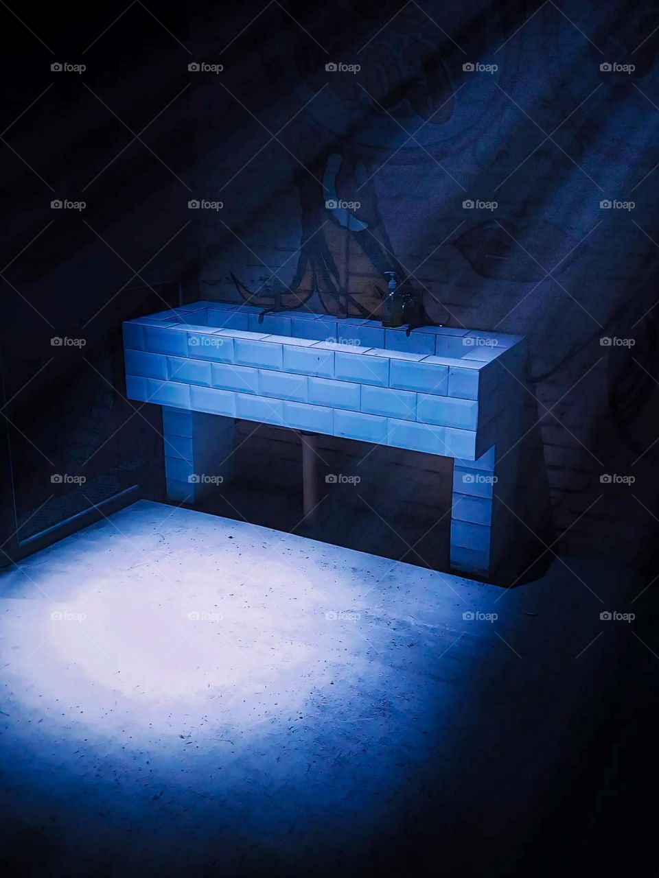 Portrait of a table made of white blocks and illuminated by blue light, with shadows creating a dramatic effect