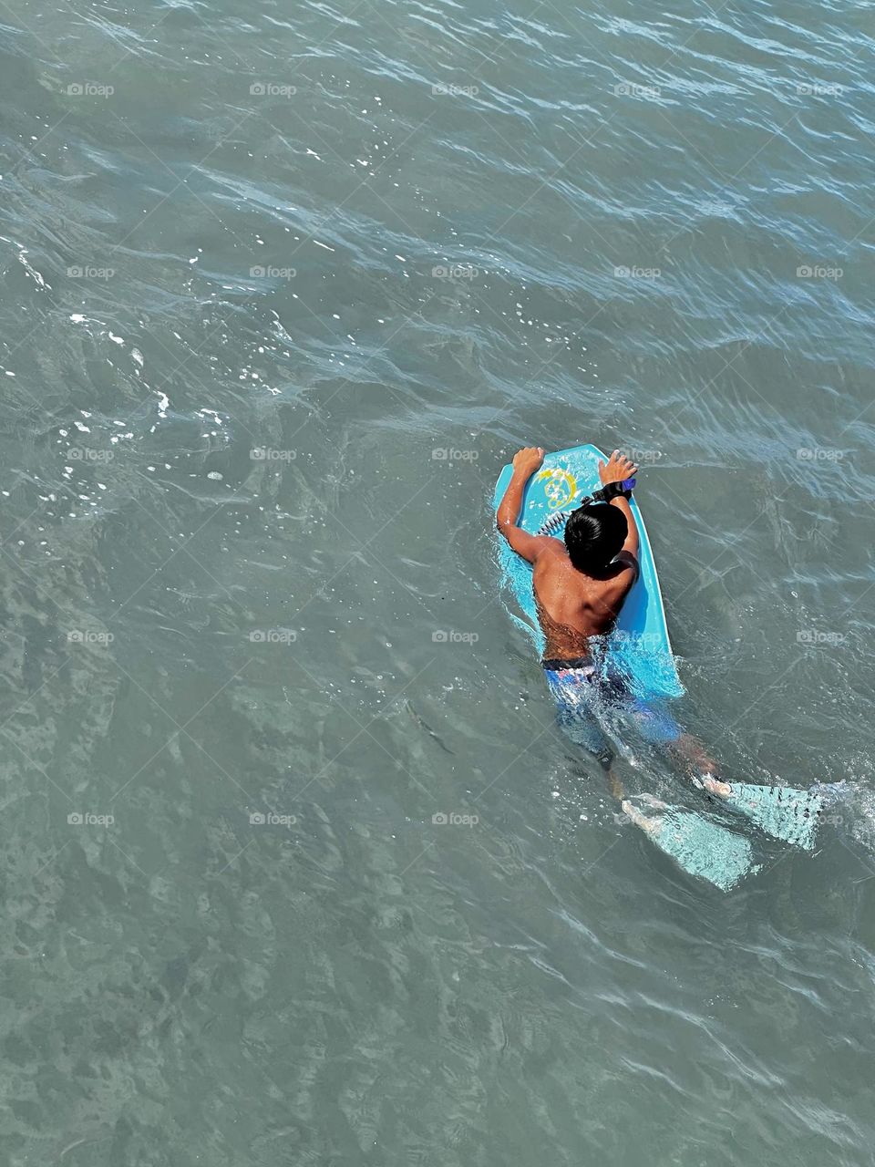 A young water man on a boogie board ready to catch his next wave near Queens Beach in Waikiki