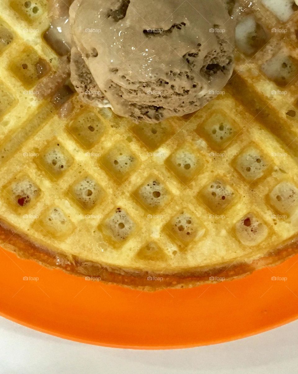 Summer treats: Waffle served with scoop of chocolate ice cream on an orange plate