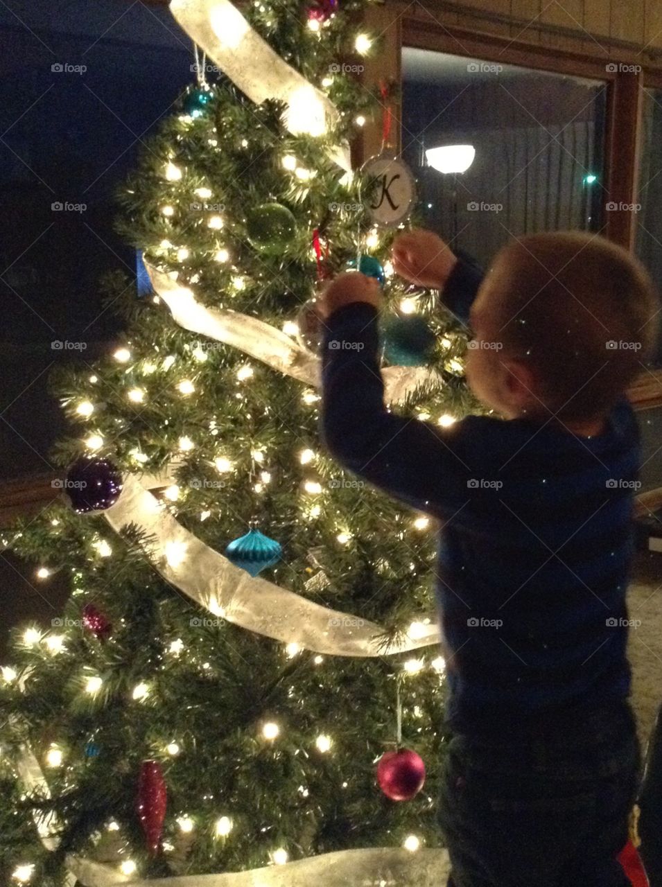 Decorating the tree. Little boy hanging ornaments