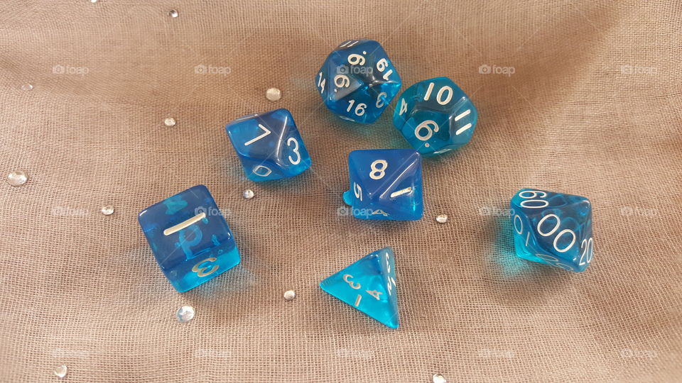 A lovely set of transparent blue dice sitting on a light brown scarf.