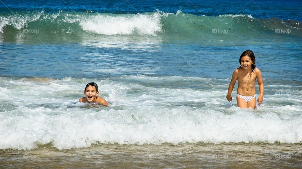 Two children enjoy bathing on the beach