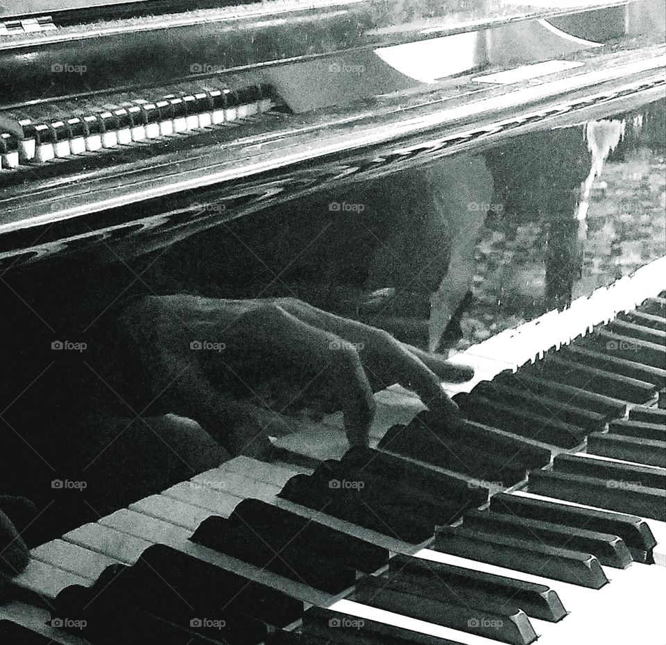 reflection of man's hand on shiny baby grand while playing, grayscale