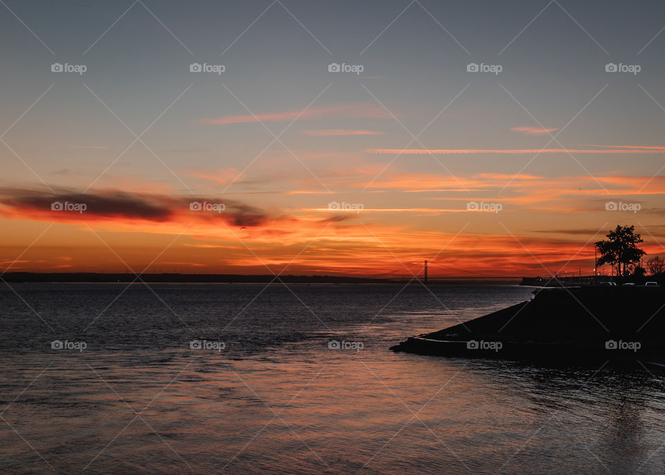 Blazing sunset over the river Humber and bridge and bird flying by