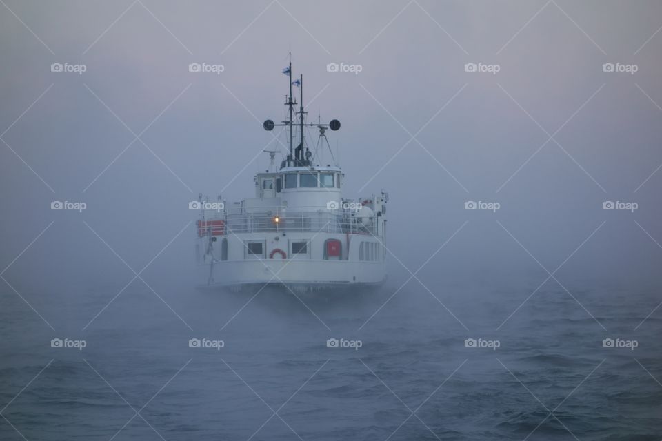 Ferry departing  Suomenlinna fortress island on Baltic sea in midst of thick sea smoke or fog on extremely cold January morning at dawn in Helsinki, Finland on 5 January 2016.