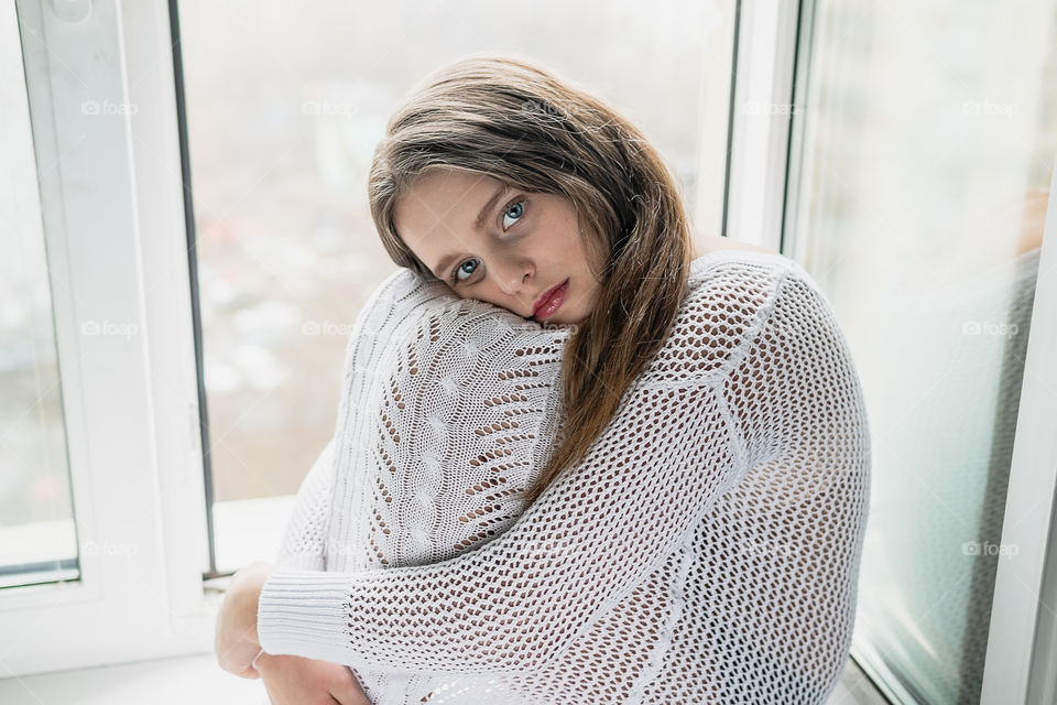 Girl is sitting by the window