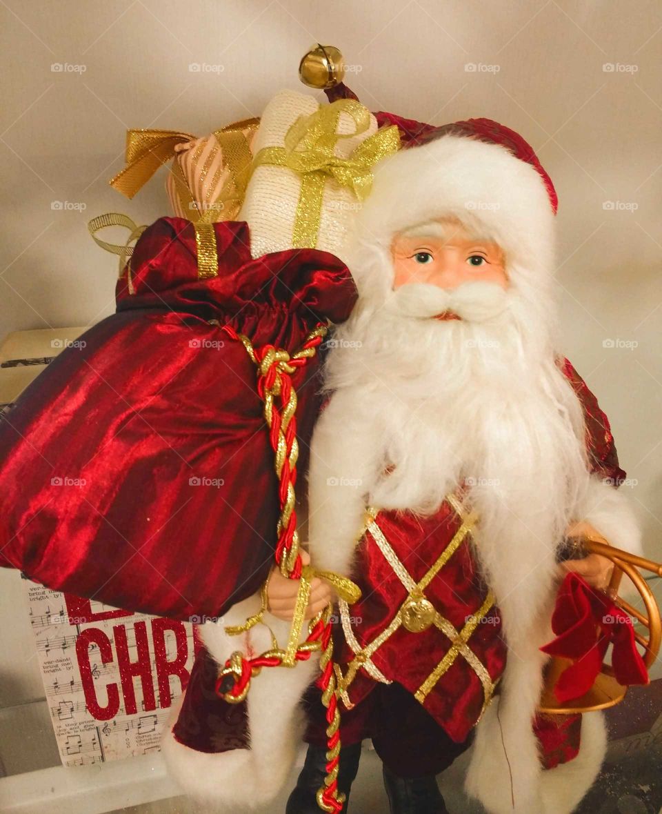 A Christmas decoration featuring Santa with a red sack of children's gifts
