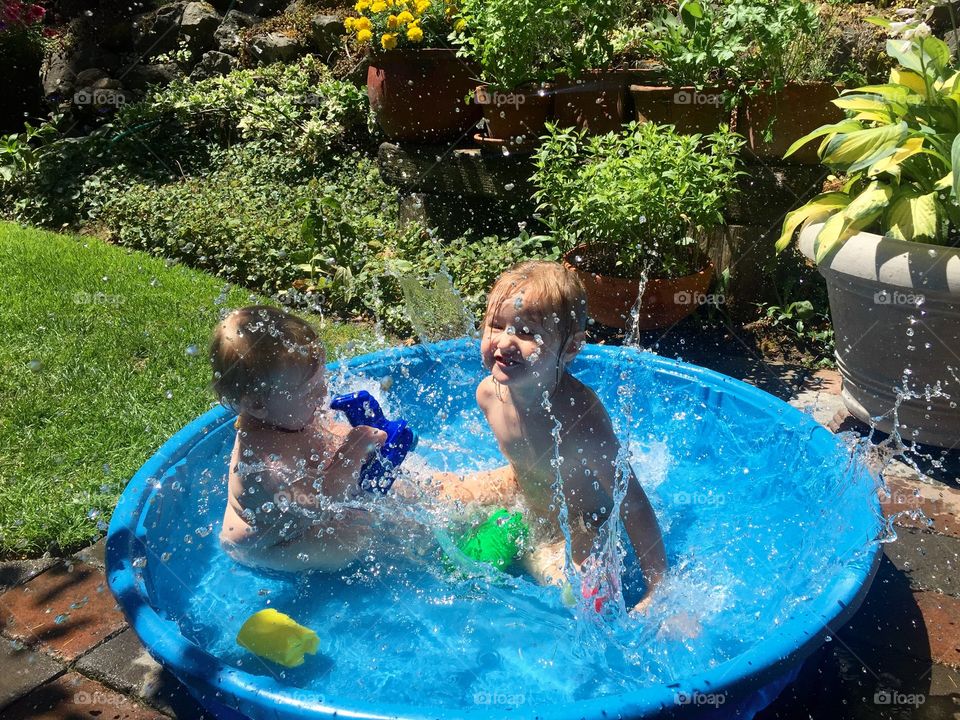 Brother and sister bathing in small blue tub